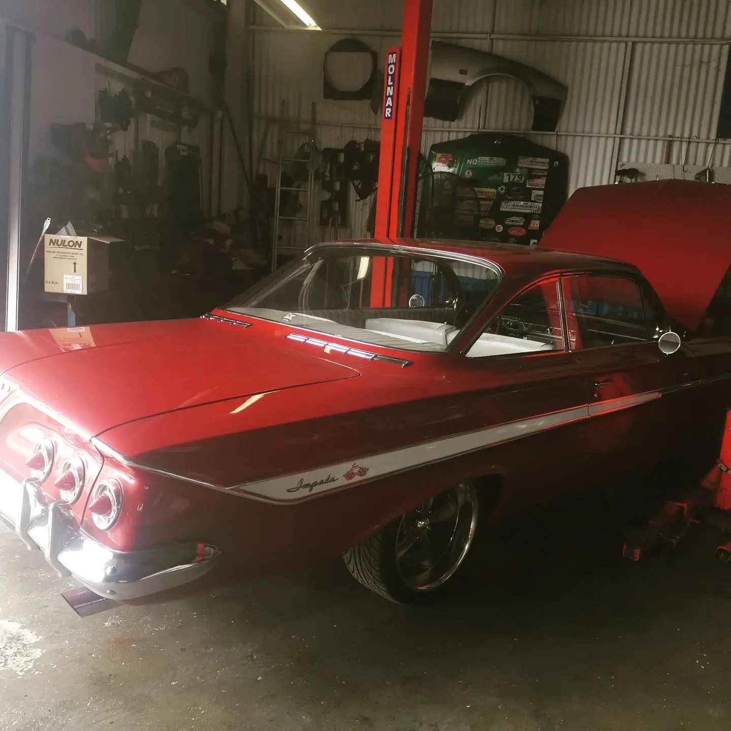 Red 1961 Chevrolet Impala on a hoist in the S & A Automotive workshop in Cairns